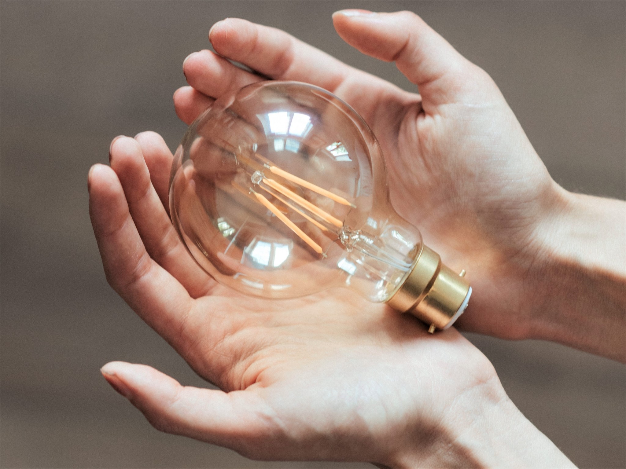 Woman holding a lightbulb in the palms of her hands, representing, natural resource protection, energy saving, sustainability, and responsible tourism.