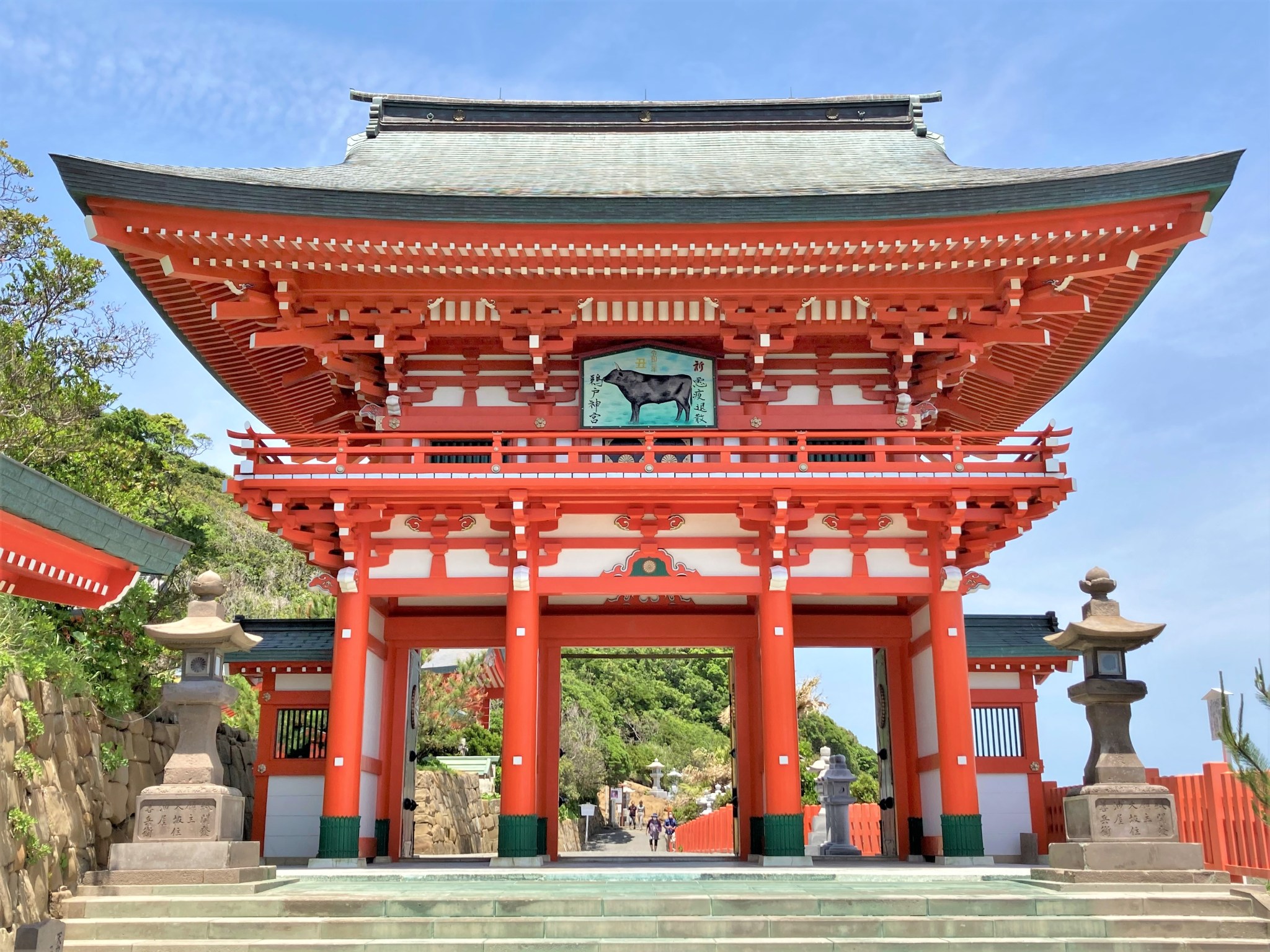 A bright red torii gate set against blue sky at the entrance of Udo Shrine in Miyazaki, Japan.