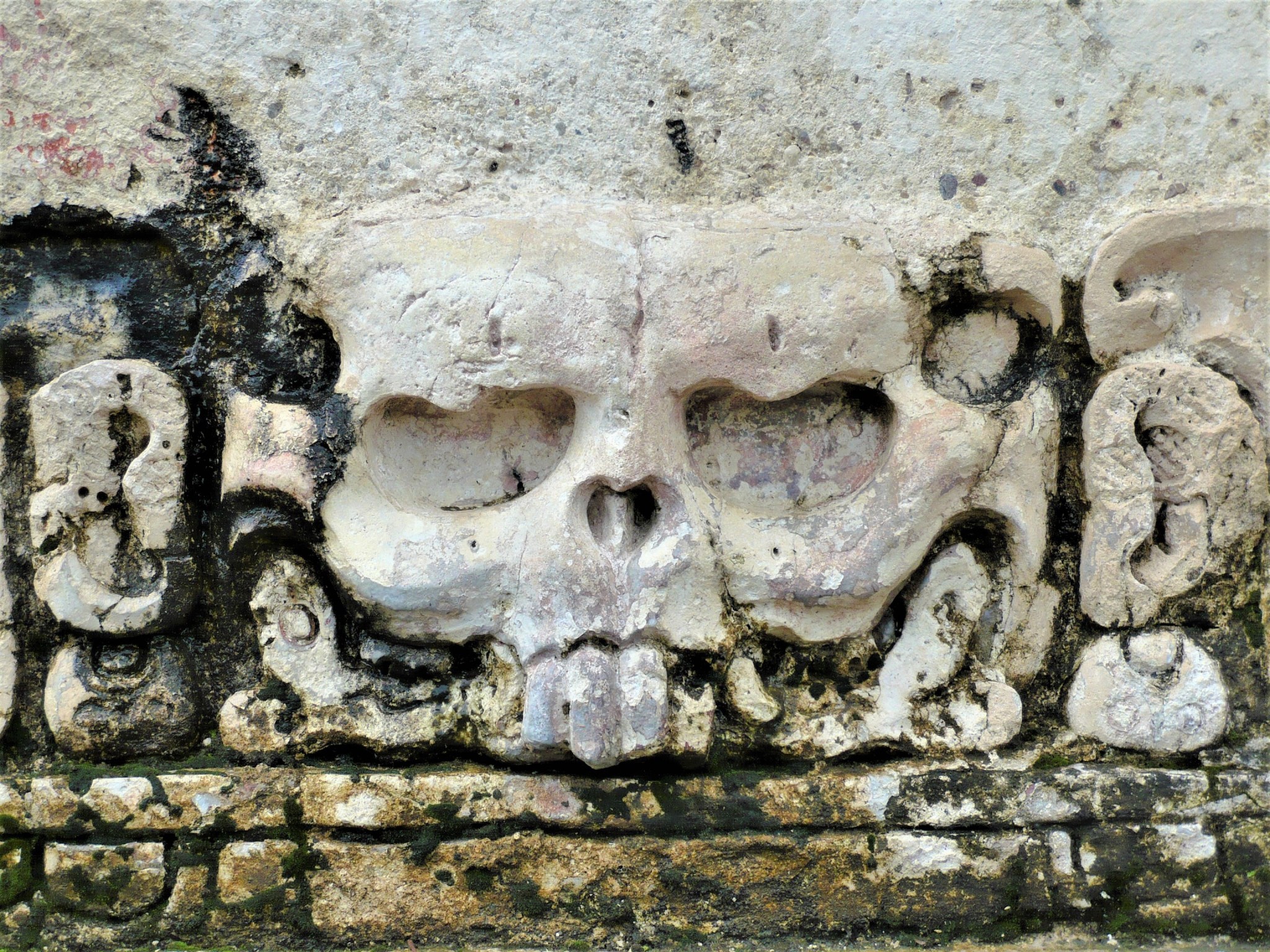 Raised relief of a grotesque stone face chiselled on a Mayan temple wall.
