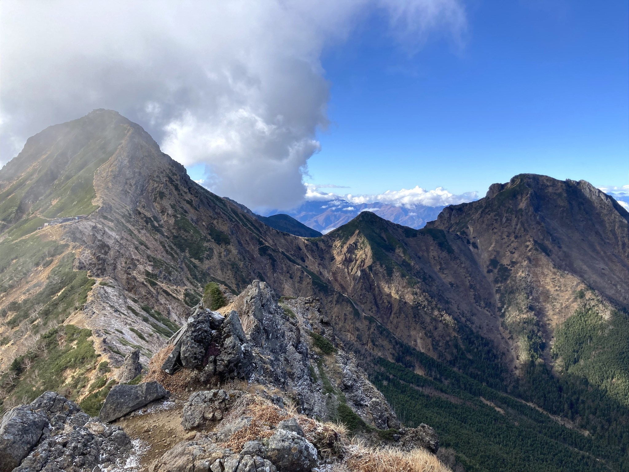 The summits of Mount Akadake and Mount Amidadake of the Yatsugatake mountain range, connected by a cloud-crested ridgeline.